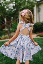 Load image into Gallery viewer, Young girl in a floral dress twirling outdoors

