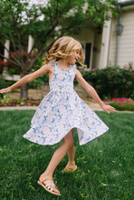 Load image into Gallery viewer, Young girl in a floral dress twirling on grass in a garden setting
