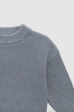 Load image into Gallery viewer, Close-up of a blue knitted sweater on a light gray background
