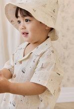 Load image into Gallery viewer, Child wearing a light-colored hat and shirt with a subtle pattern.
