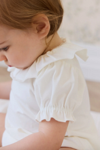 Load image into Gallery viewer, Child wearing a white blouse with ruffled sleeves on a soft background
