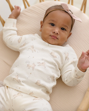 Load image into Gallery viewer, Baby lying on a pink cushion wearing a white outfit with animal prints and a pink headband.
