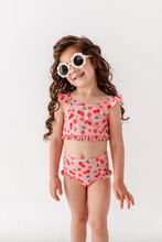 Load image into Gallery viewer, Young girl wearing a red swimsuit with cherry pattern and sunglasses on a white background
