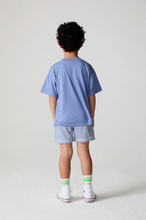 Load image into Gallery viewer, Child wearing a blue t-shirt and patterned shorts on a plain background
