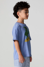 Load image into Gallery viewer, Child wearing a blue t-shirt with a graphic design on a plain background

