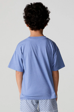 Load image into Gallery viewer, Child wearing a blue t-shirt and checkered pants on a plain background
