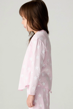 Load image into Gallery viewer, A young girl in profile wearing a light pink long-sleeve pajama top with a white star pattern, set against a plain light gray studio background.
