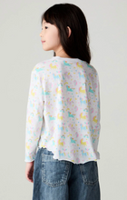 Load image into Gallery viewer, A child model shown from the back wearing a white long-sleeve top with a pastel unicorn print and blue jeans, against a plain light gray studio background.
