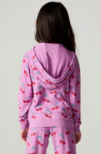 Load image into Gallery viewer, A child model shown from the back wearing a pink zip-up hoodie and matching pants set, both covered in a red cherry print with green stems, against a plain light gray background.
