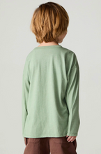 Load image into Gallery viewer, A child shown from the back wearing a sage green long-sleeve t-shirt and brown pants, photographed against a plain light gray studio background.
