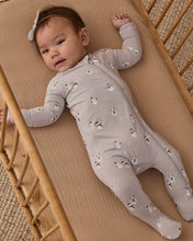 Load image into Gallery viewer, Baby wearing a gray snowman-print footie and bow headband, lying in a wooden crib with one arm raised.
