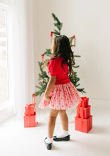 Load image into Gallery viewer, Rear three-quarter view of a child wearing the pink Dainty Bows tulle skirt, showing its gathered shape and above-knee length.
