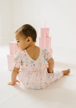 Load image into Gallery viewer, Rear view of a seated baby wearing the Sugar Plum romper, showing the V-shaped neckline and relaxed fit.

