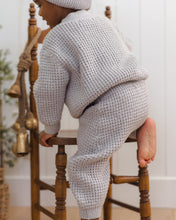Load image into Gallery viewer, Back view of a child climbing onto a wooden chair, wearing a fog gray chunky knit sweater and matching pants.
