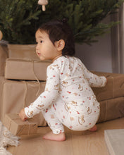 Load image into Gallery viewer, Back view of a child crouching beside wrapped gifts, wearing cream pajamas with an allover holiday toy print.
