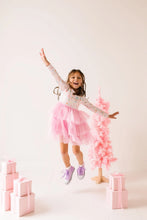 Load image into Gallery viewer, Child jumping with arms spread in a Sugar Plum tutu dress and purple high-top sneakers.
