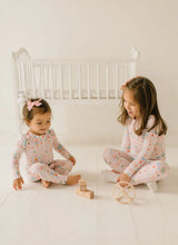 Load image into Gallery viewer, Two children playing with wooden toys in matching Sugar Plum prints, one in two-piece pajamas and one in a zip sleeper.
