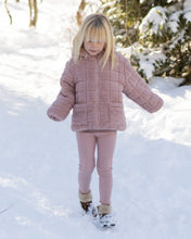 Load image into Gallery viewer, A young girl with blonde hair stands in the snow wearing a dusty pink quilted fleece jacket, matching pink ribbed leggings, and winter boots.
