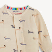 Load image into Gallery viewer, Close-up of the cream footie with its front closure fastened, showing dachshunds wearing hats and scarves.

