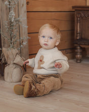 Load image into Gallery viewer, Relaxed Raglan Sweater in Gingerbread Man, cream on a toddler seated on a stool
