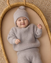 Load image into Gallery viewer, Baby lying in a woven basket wearing a fog gray chunky knit sweater, matching pants, and a pom-pom hat.
