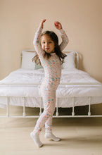 Load image into Gallery viewer, Full-length side view of a child twirling in pale pink Sugar Plum pajamas and white socks beside a bed.
